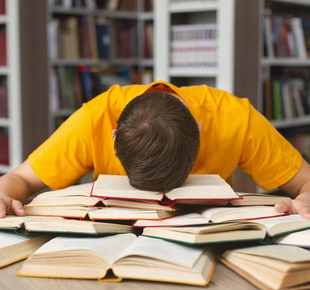 Student studying hard exam and sleeping on books in library, free space